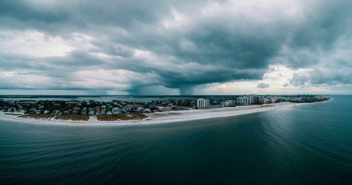 Aerial shot of a beachfront city with dramatic clouds over the ocean. Perfect for travel and nature themes.