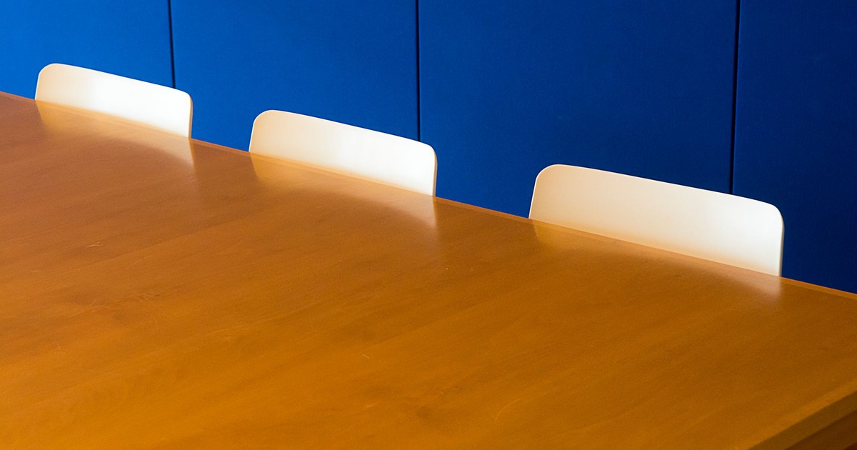 A clean and modern indoor meeting room with a wooden table against a blue wall.