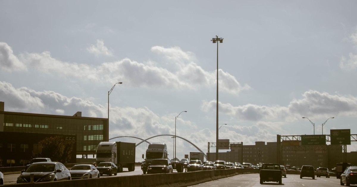Traffic flows on a Dallas highway under a cloudy sky with visible city skyline. Perfect for urban lifestyle themes.