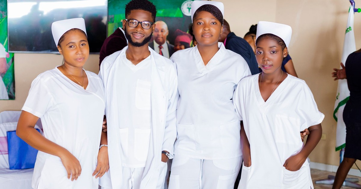 Four healthcare professionals wearing white uniforms, posing indoors.