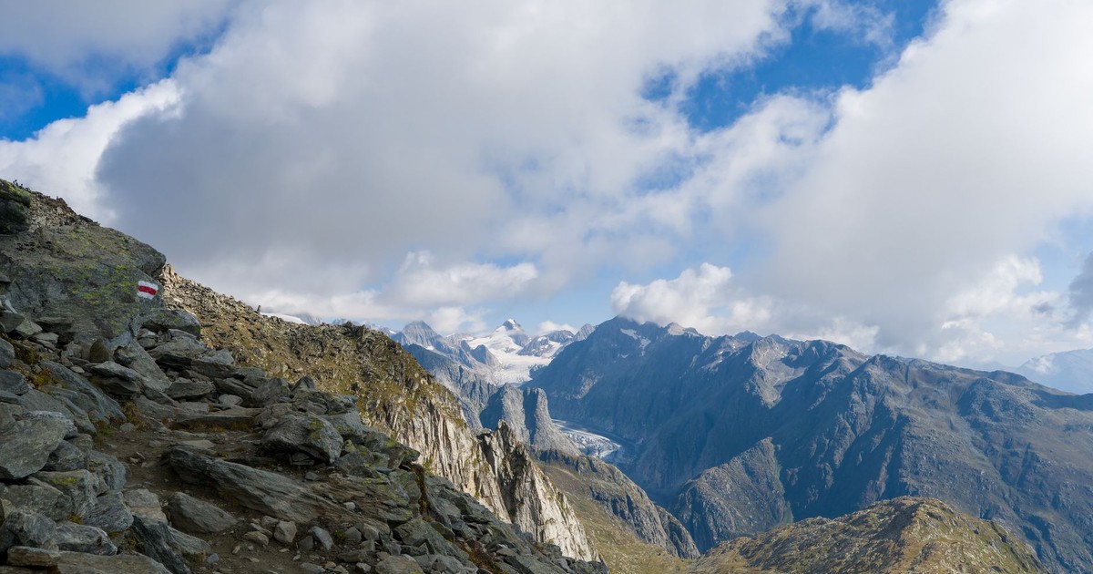 Stunning view of rocky alpine path in Swiss Alps with clear skies and majestic peaks.