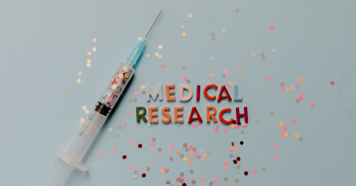 Close-up of a syringe with colorful confetti on medical research theme.