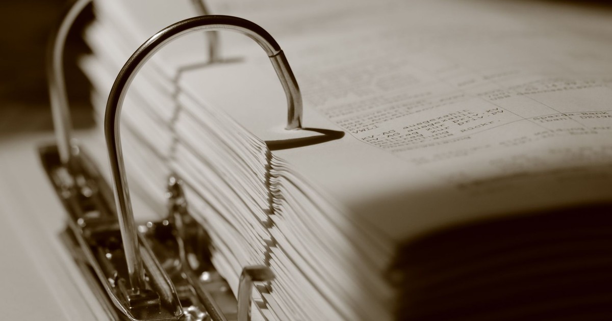 Detailed sepia close-up of a binder filled with documents, emphasizing texture.