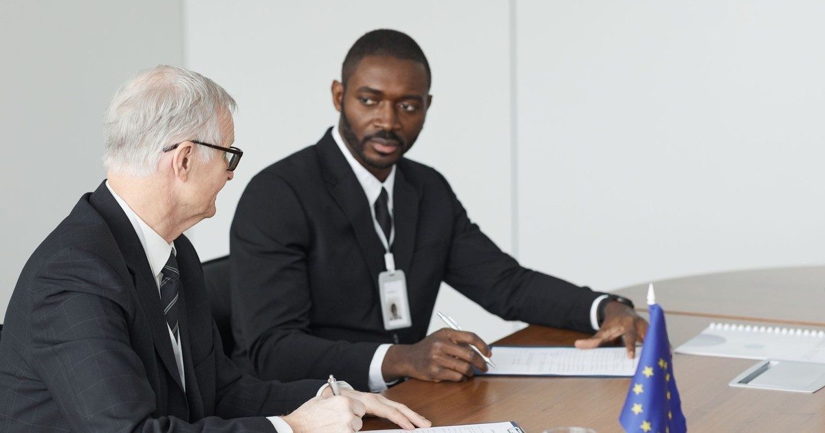 Two businessmen in formal suits discussing at a conference table.