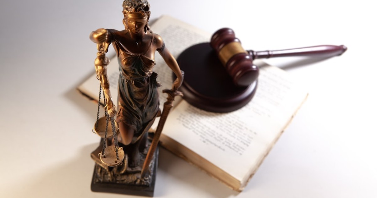 Statue of justice, gavel, and open book on table.