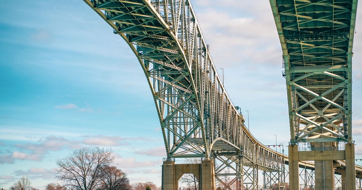 Low-angle shot of the Blue Water Bridge connecting Canada and Michigan, under a clear blue sky.