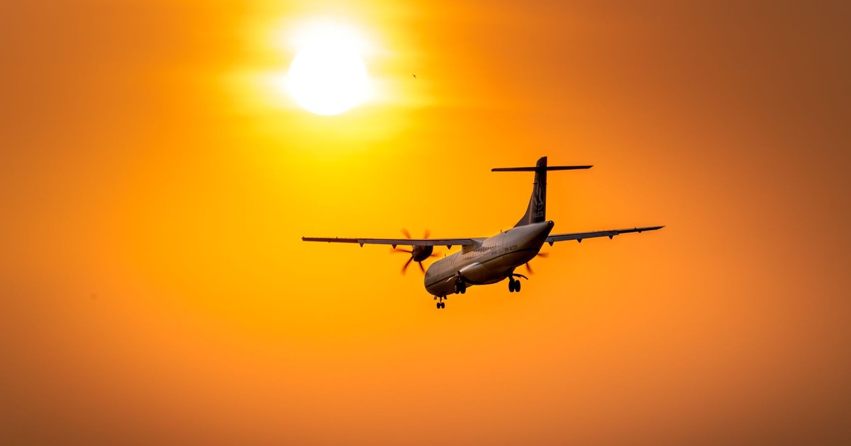 A dramatic silhouette of an airplane flying against a vibrant sunset sky, capturing a sense of adventure and travel.