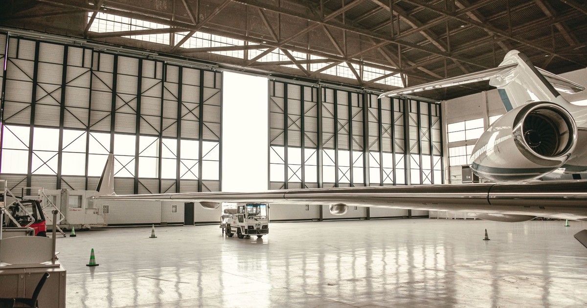 View of a private jet in a spacious hangar with architectural design elements.