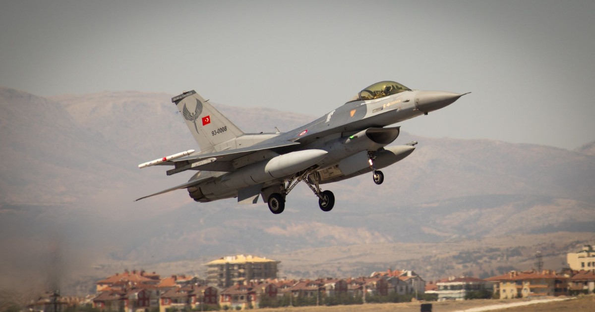 A Turkish fighter jet soaring above Konya's landscape during day.