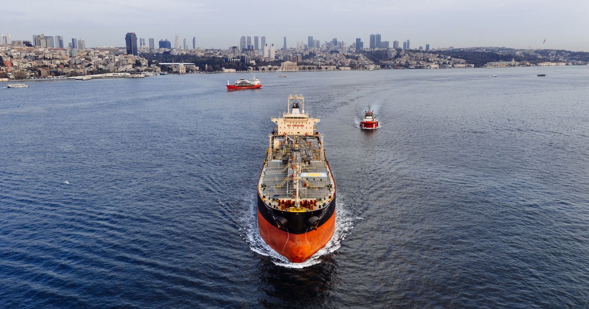 A stunning aerial shot of a cargo ship navigating the Bosphorus Strait in Istanbul, Turkey, with a city skyline.