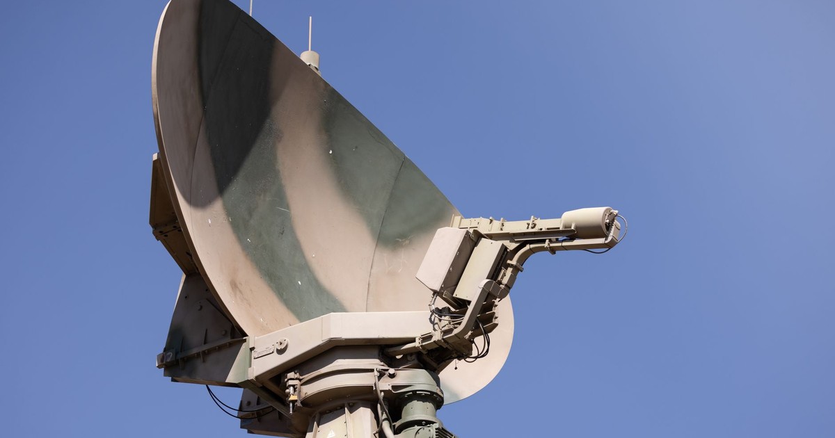 Close-up of a military radar system with a clear blue sky as background, showcasing advanced communication technology.