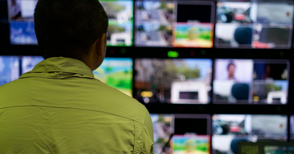 Man in a control room overseeing multiple monitors displaying various scenes.