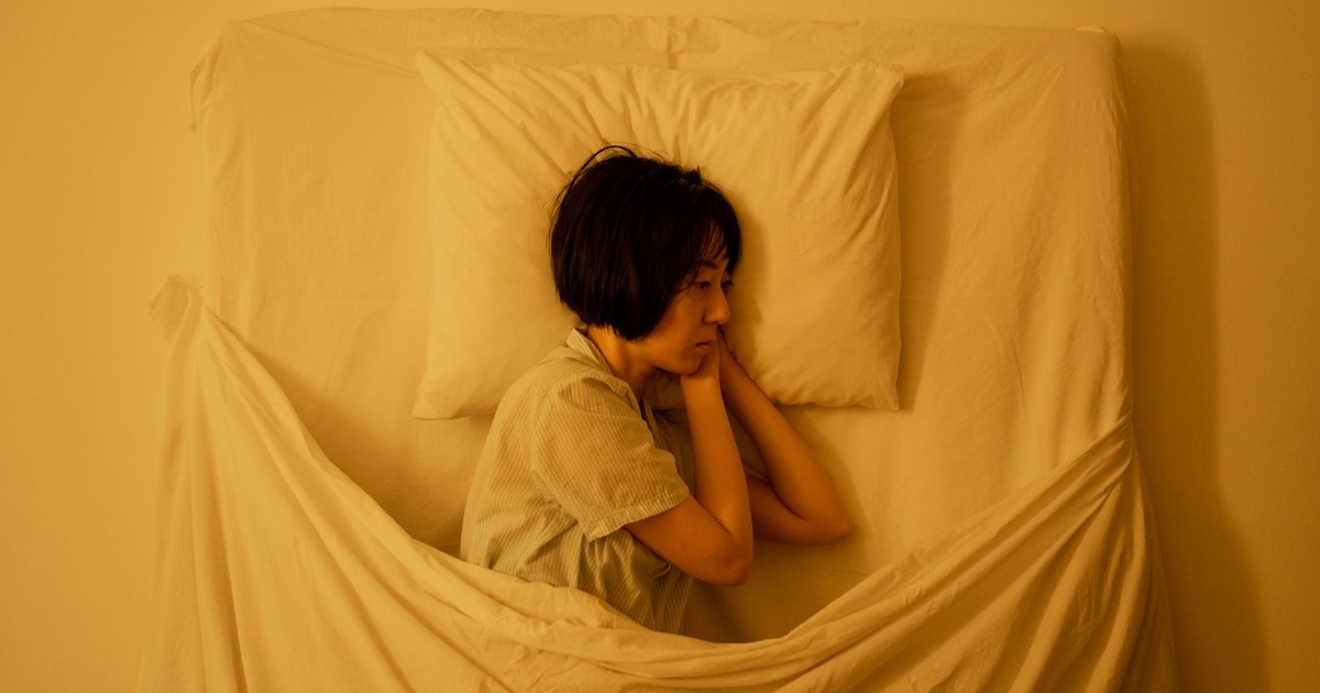 A woman lies in bed, reflecting deep emotions related to mental health issues.