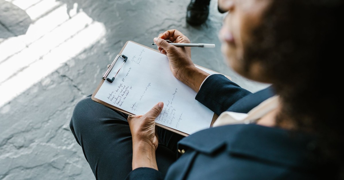 Close-up of a therapist writing notes on clipboard during a counseling session.