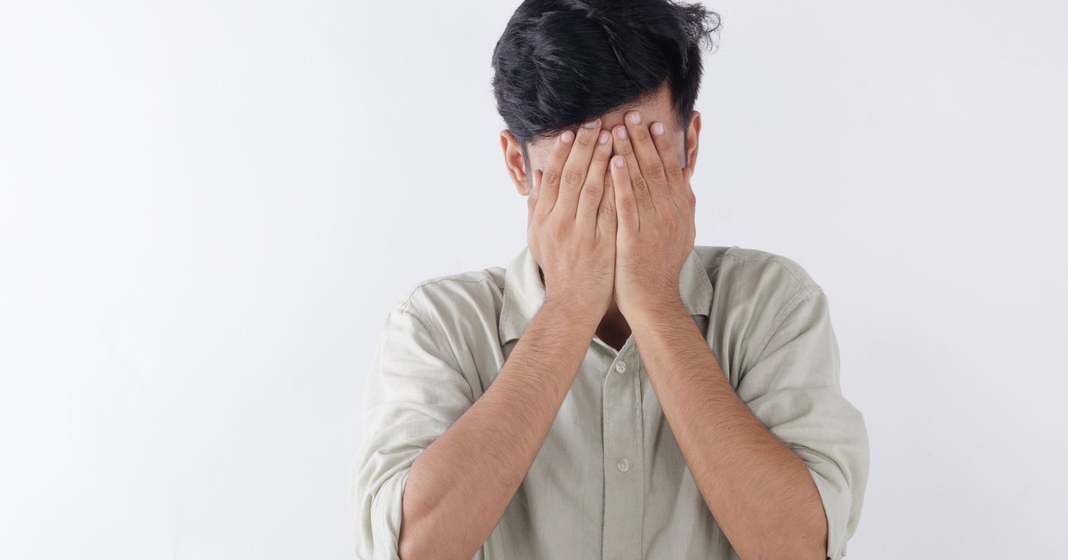 A man covering his face with hands, expressing feelings of stress and emotional struggle.