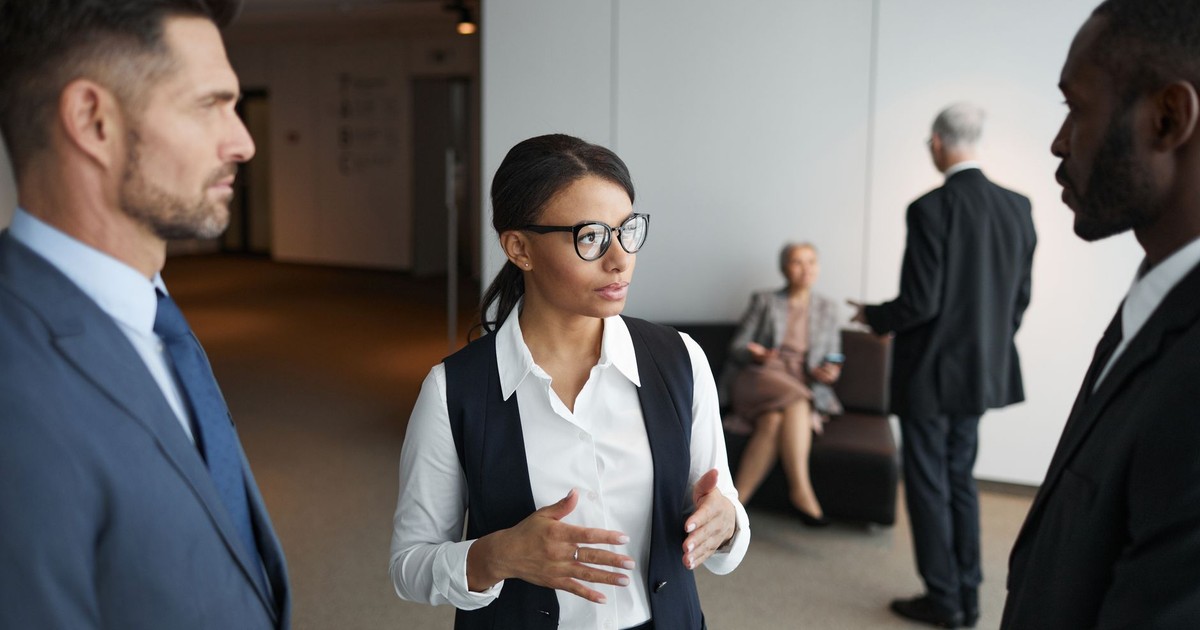 A diverse group of professionals engaged in a serious meeting in an office setting.