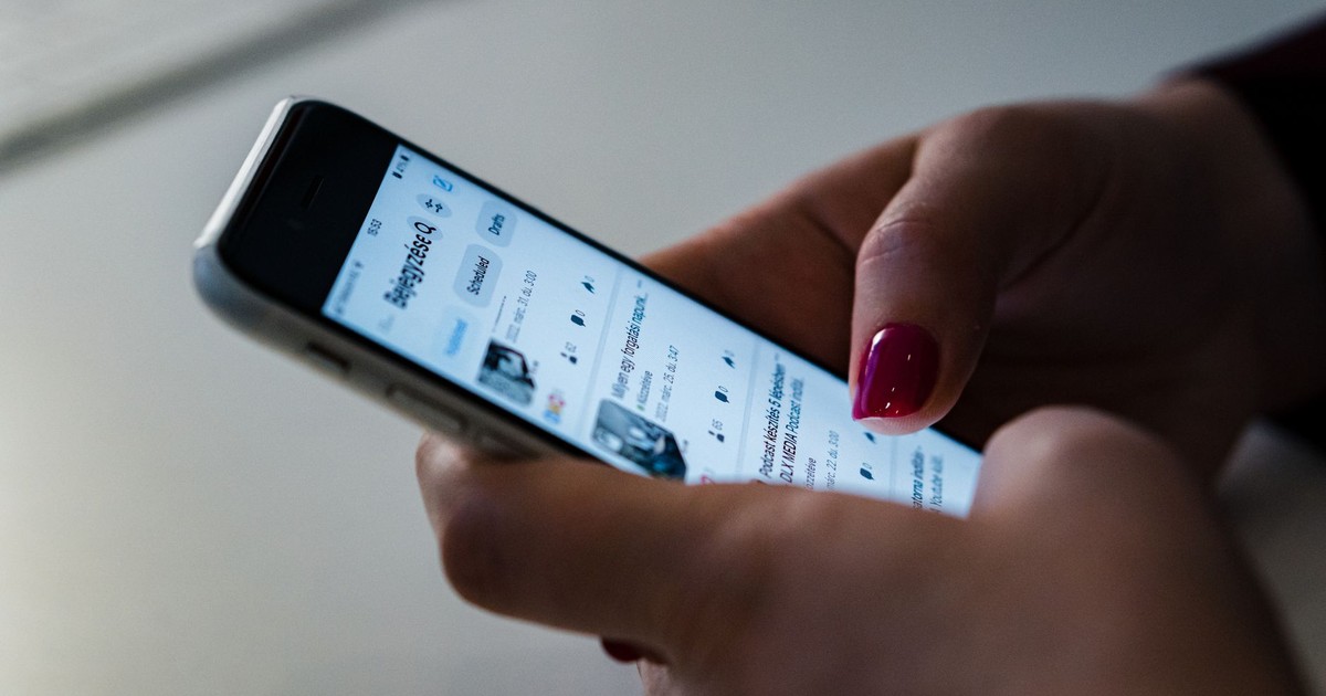 Person holding a smartphone and browsing social media, showcasing touchscreen interaction.