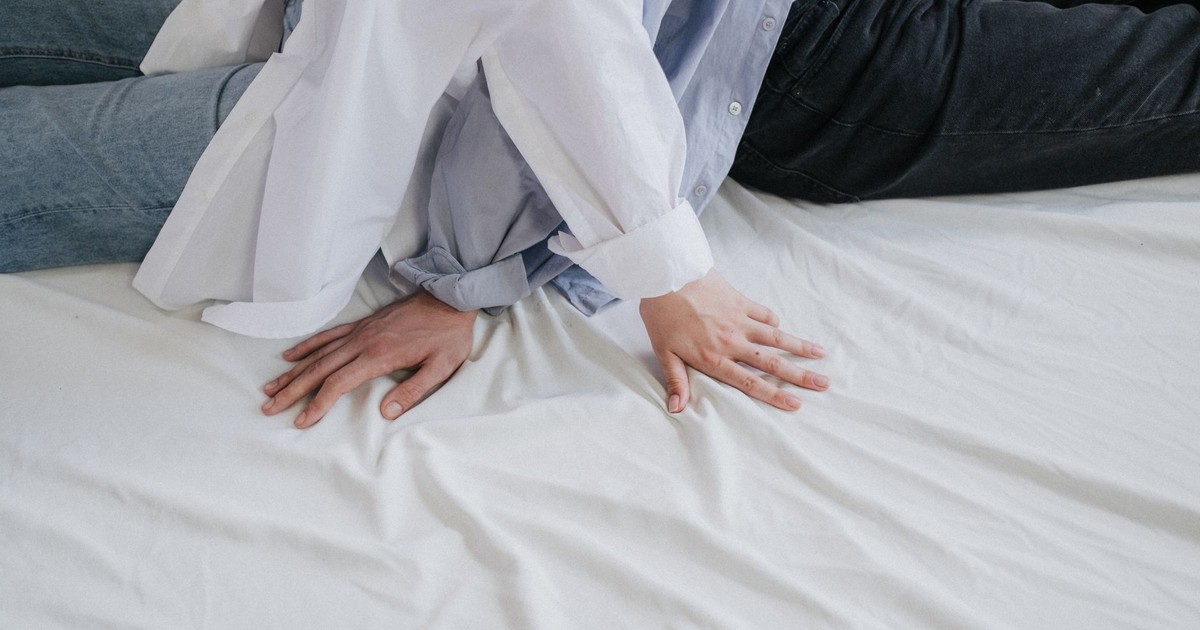 A close-up of a couple's hands resting on a bed, highlighting minimalist style and relaxation.