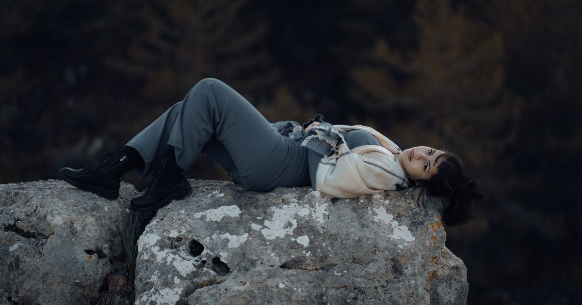 A serene moment of a woman lying on a large rock in nature, showcasing tranquility.