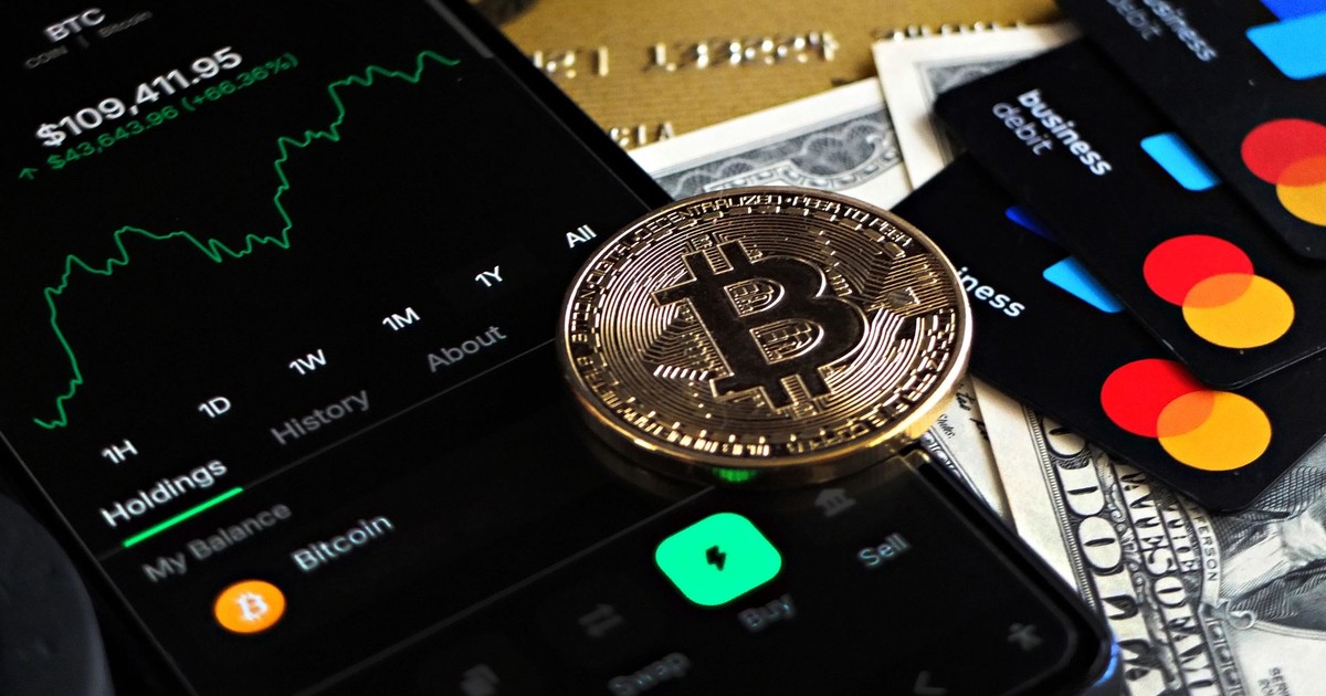 Bitcoin coin with financial data, credit cards, and currency on a desk.