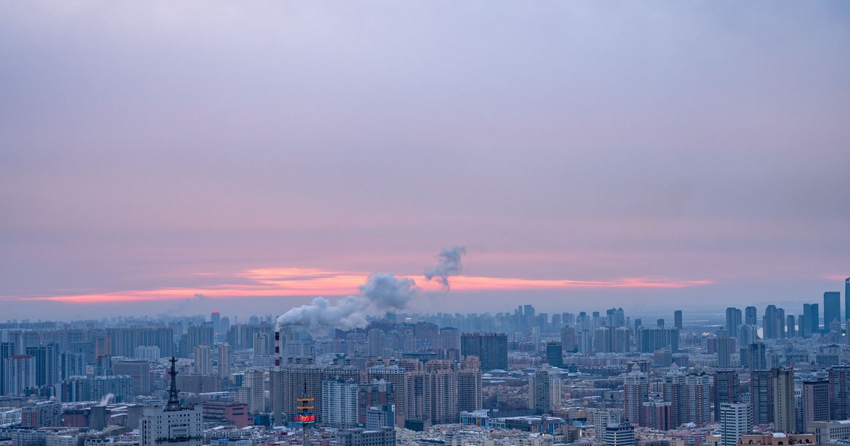 Aerial view of Harbin at sunset, showcasing urban skyline and industrial smoke.