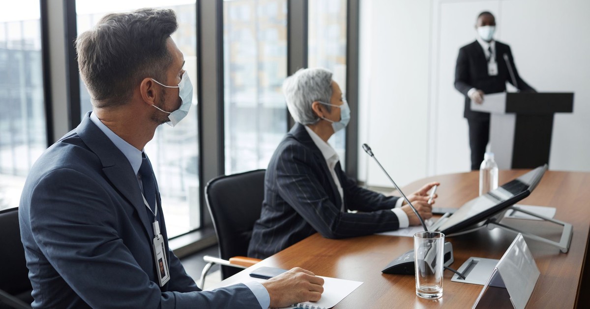 Business professionals in a meeting room wearing face masks for safety.