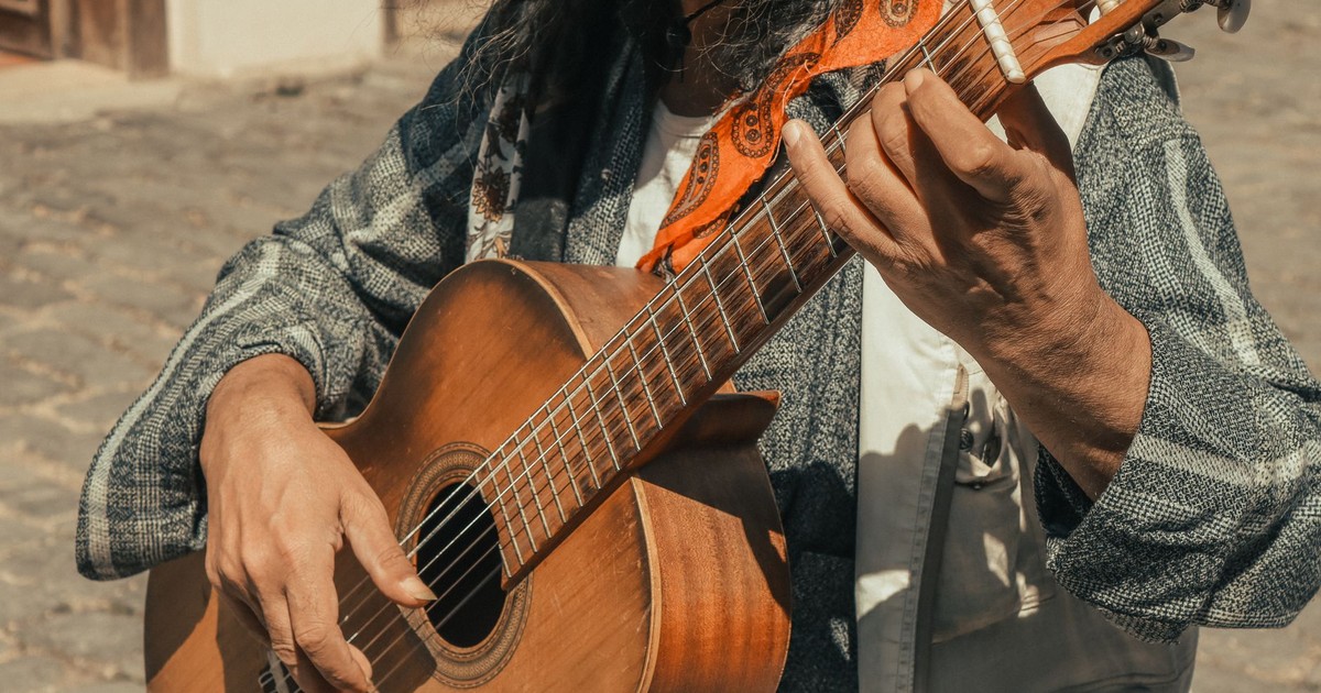 Close-up of a street musician playing an acoustic guitar outdoors, showcasing intricate fingerwork.