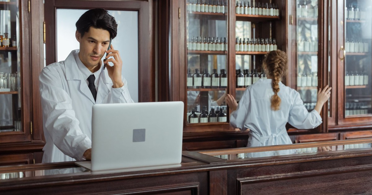 Pharmacists communicating and organizing medicines in a traditional pharmacy setting.