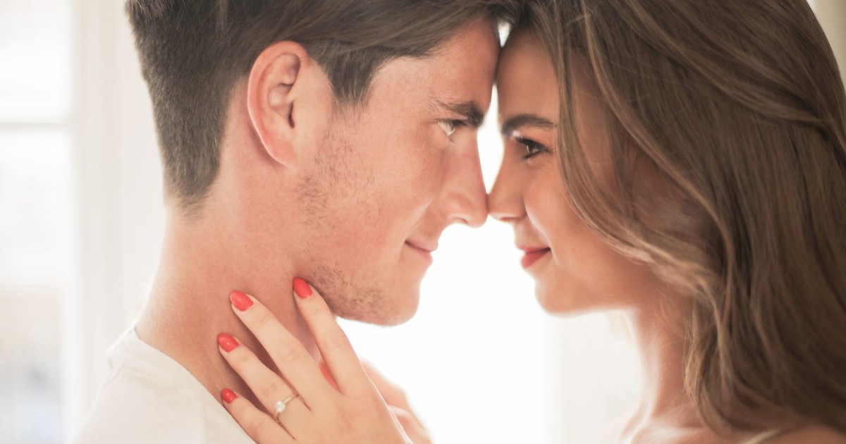 Close-up of a romantic couple embracing and smiling indoors, showcasing love and intimacy.