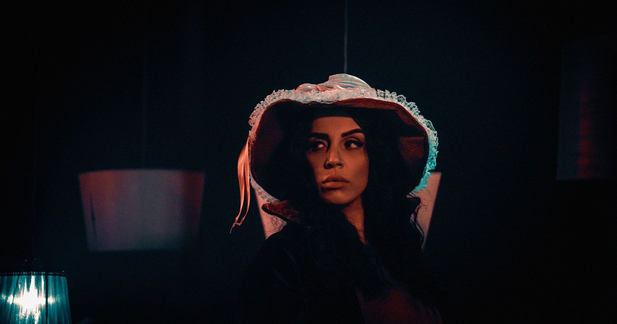 Artistic portrait of a woman in a vintage hat with dramatic lighting.