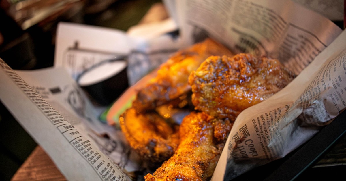 Delicious golden chicken wings served in a newspaper-lined basket, perfect for a hearty meal.