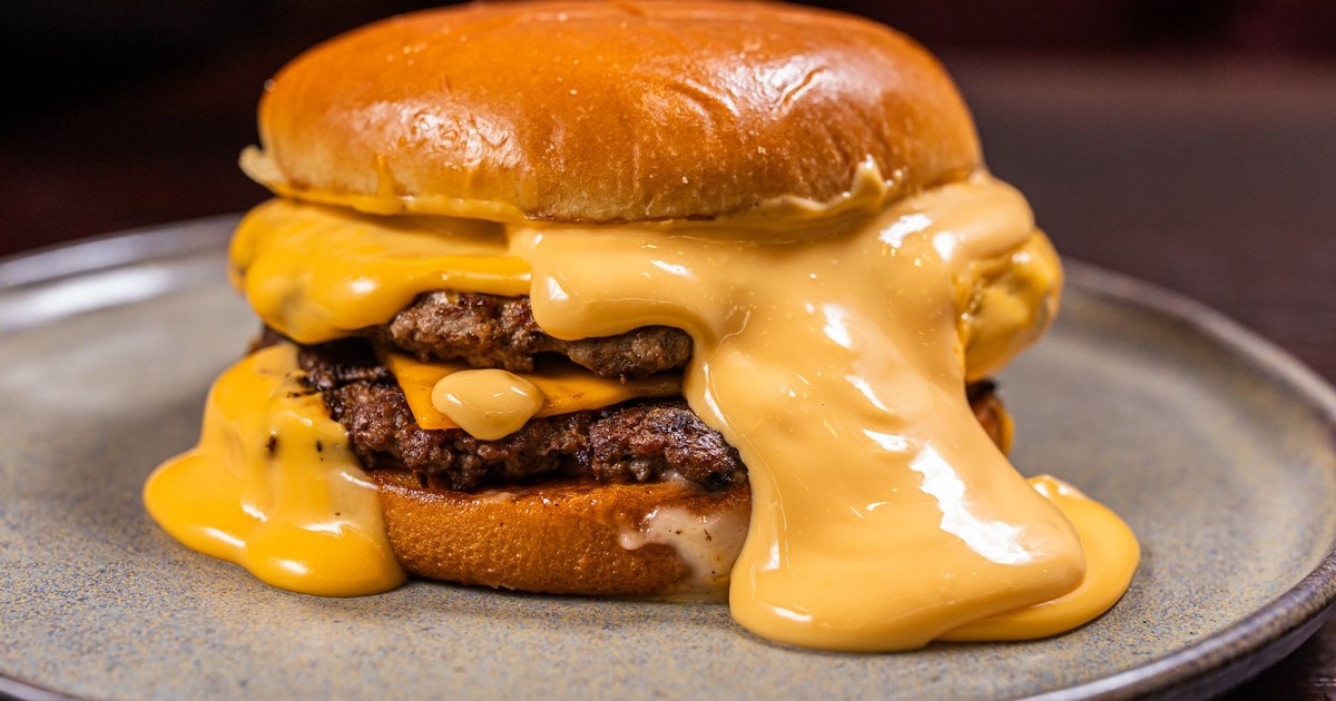 Close-up of a juicy burger with thick melted cheddar cheese, served on a plate.