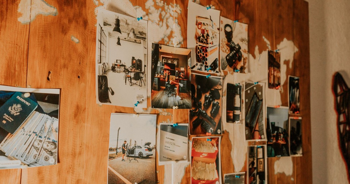 A collection of travel photos pinned on a wooden map-themed wall, evoking adventure and nostalgia.