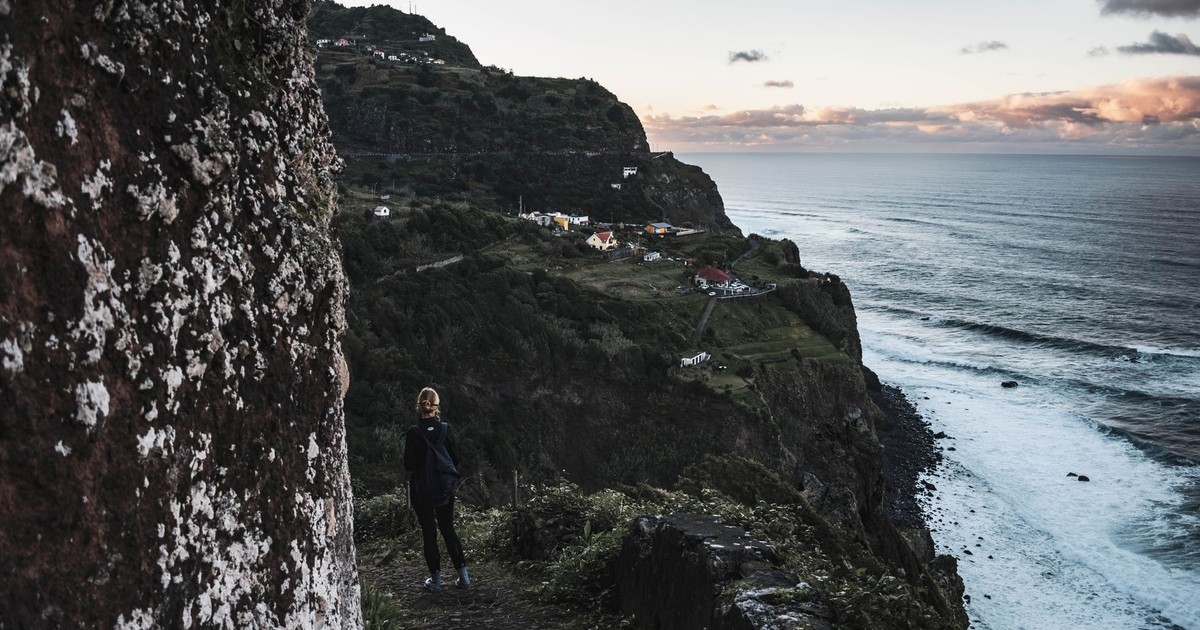 Person walking on a cliffside trail in Madeira, Portugal during the evening.