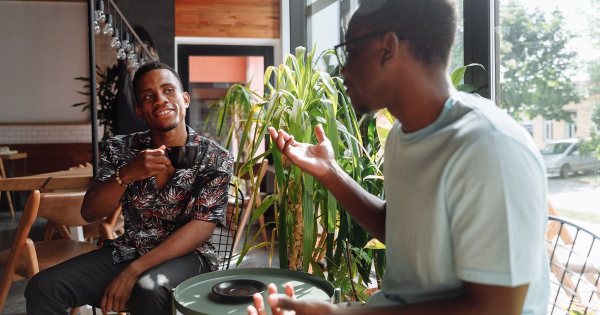 Two friends having a lively conversation over coffee in a cozy coffee shop setting.