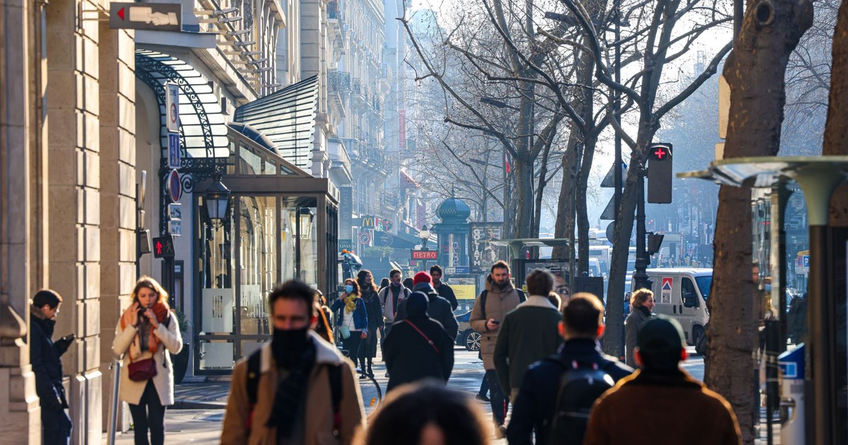 Crowded urban street with people walking on a sunny day.