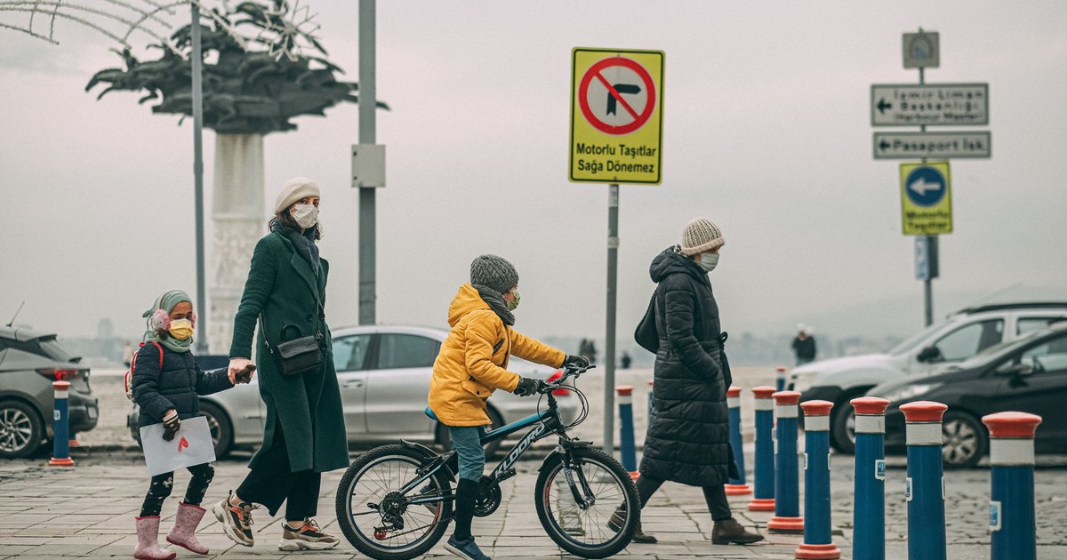 A family with children and adults crossing a city road wearing masks during daytime.