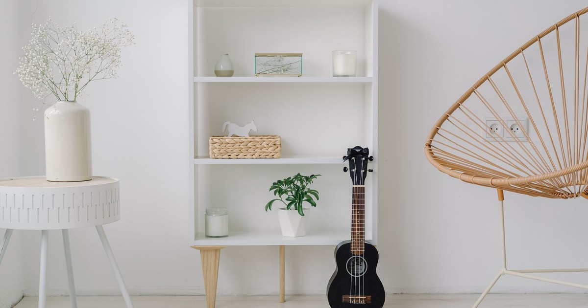 A modern minimalist living room setup featuring a ukelele, shelves, and stylish decor.