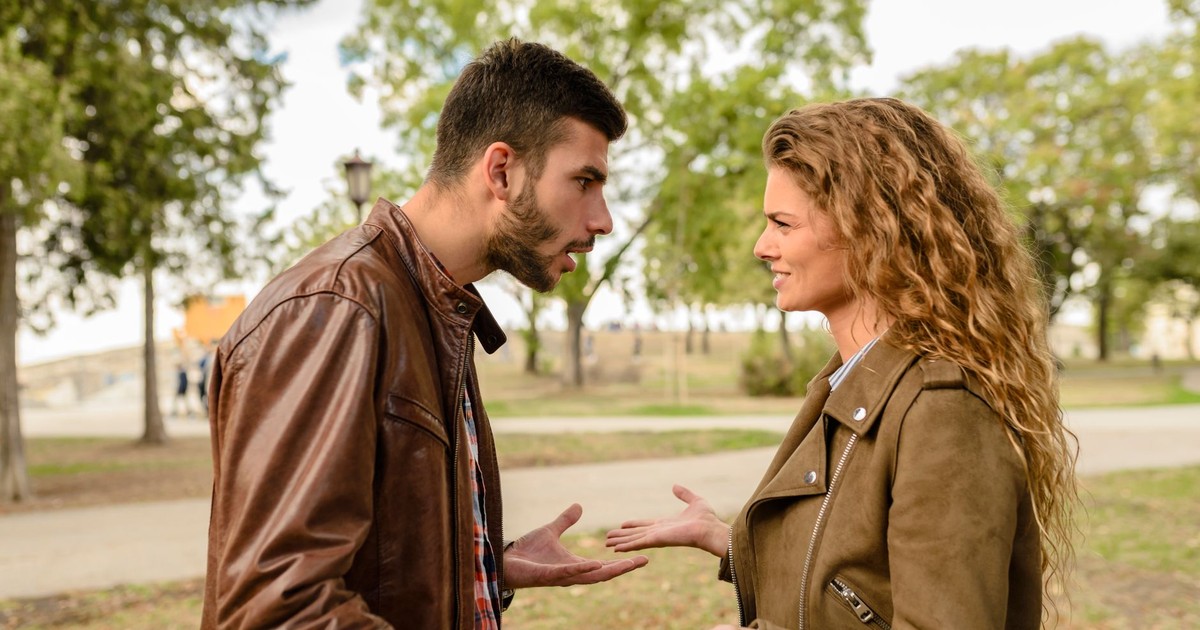 A couple having an argument outdoors, expressing frustration and conflict.