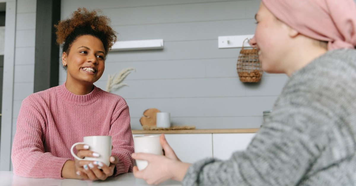 Two women share a joyful coffee moment at home, embodying friendship and warmth.