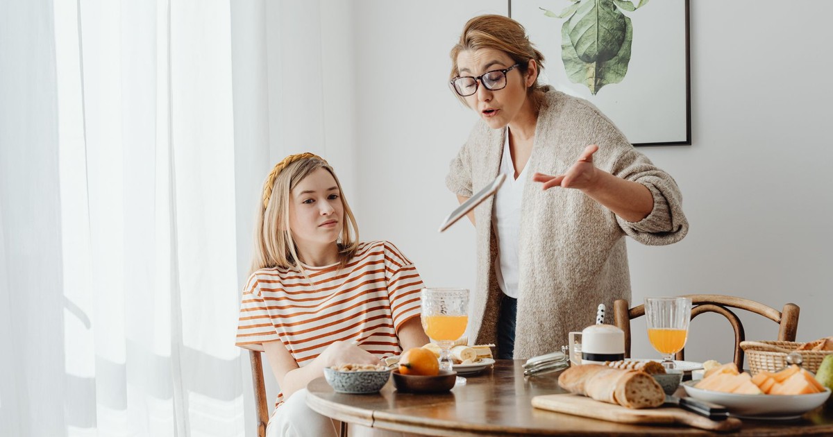 A mother and teenage daughter having a tense breakfast conversation at home.
