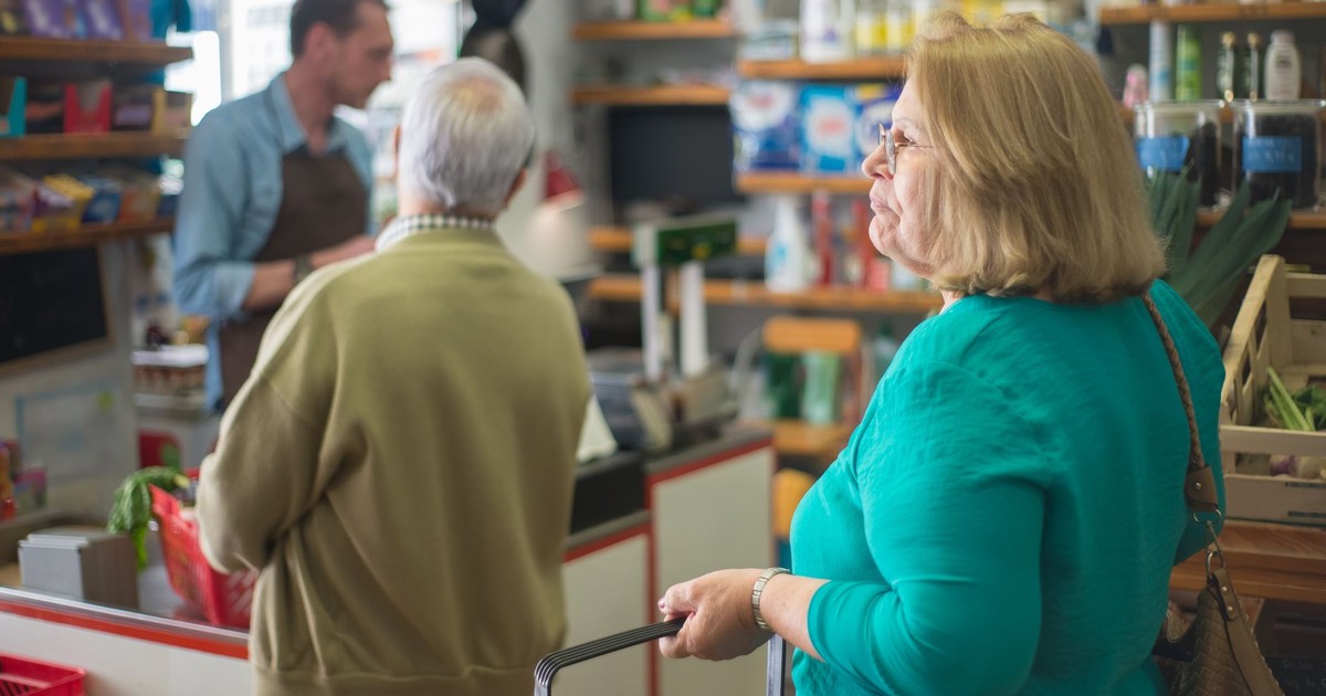Senior woman with basket shopping in a cozy Portugal grocery store.