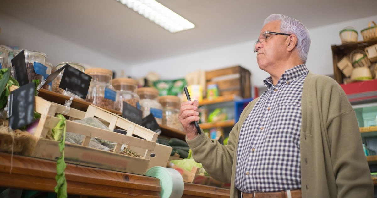 Senior man shopping in a Portuguese store, examining products with focus.