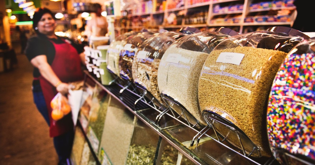 A bustling indoor market showcasing bulk goods with a friendly saleswoman.