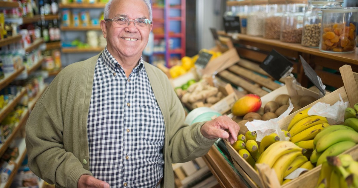 Senior man smiling while selecting fresh fruits in a grocery store.