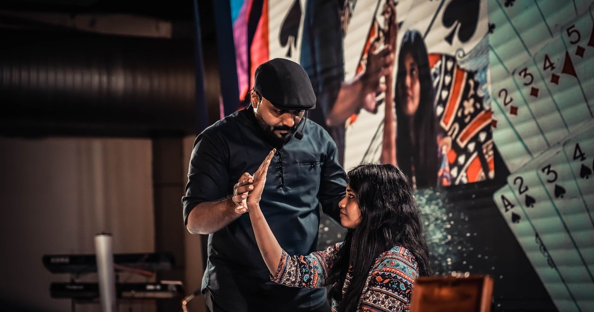 A captivating magician performing a card trick with an assistant on stage, engaging the audience.