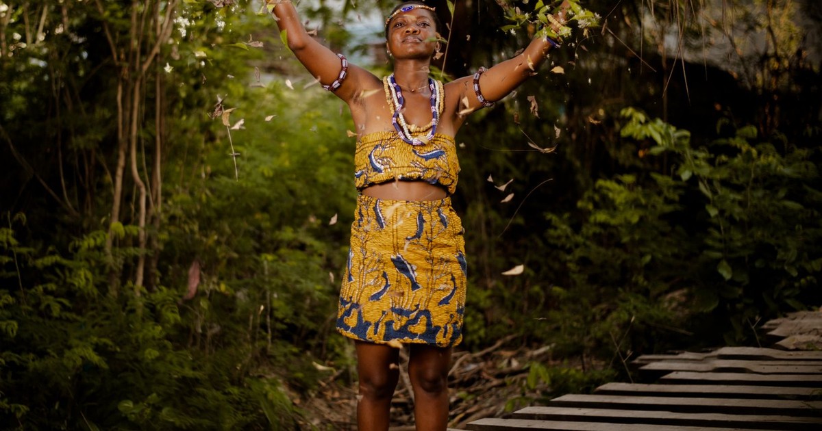A woman in traditional clothing participating in an outdoor tribal ritual.