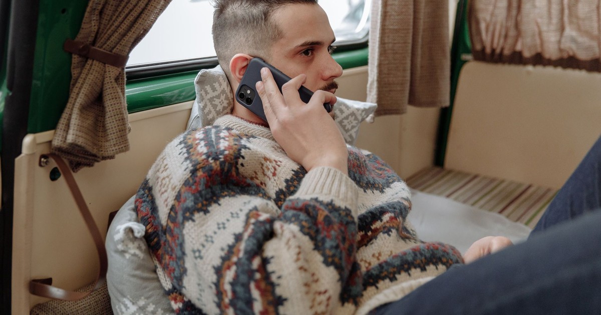 Casual adult man wearing sweater, relaxing indoors while talking on phone.
