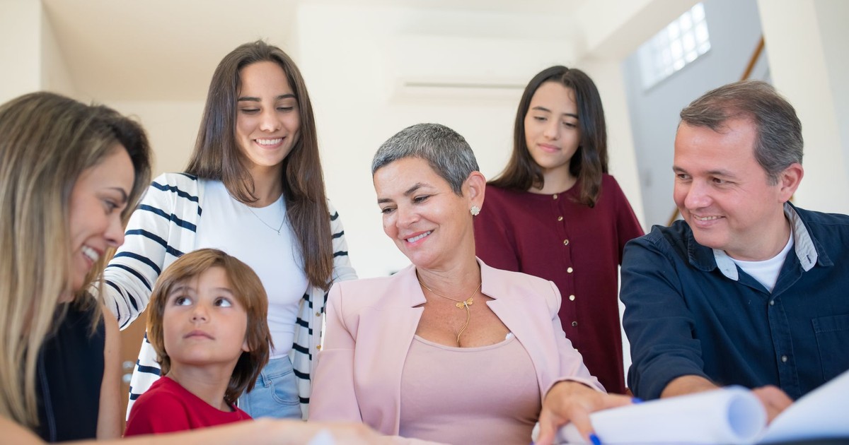 A family gathering around a table, discussing real estate documents indoors with a realtor.