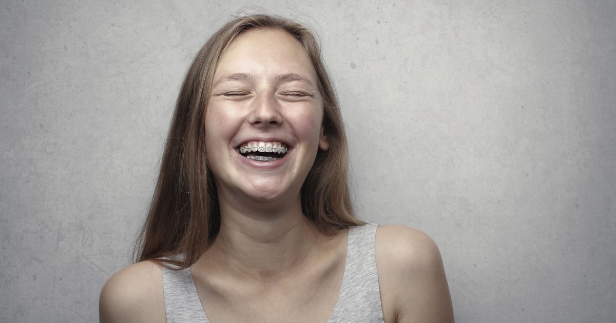 A cheerful woman with braces laughing joyfully in a casual portrait.